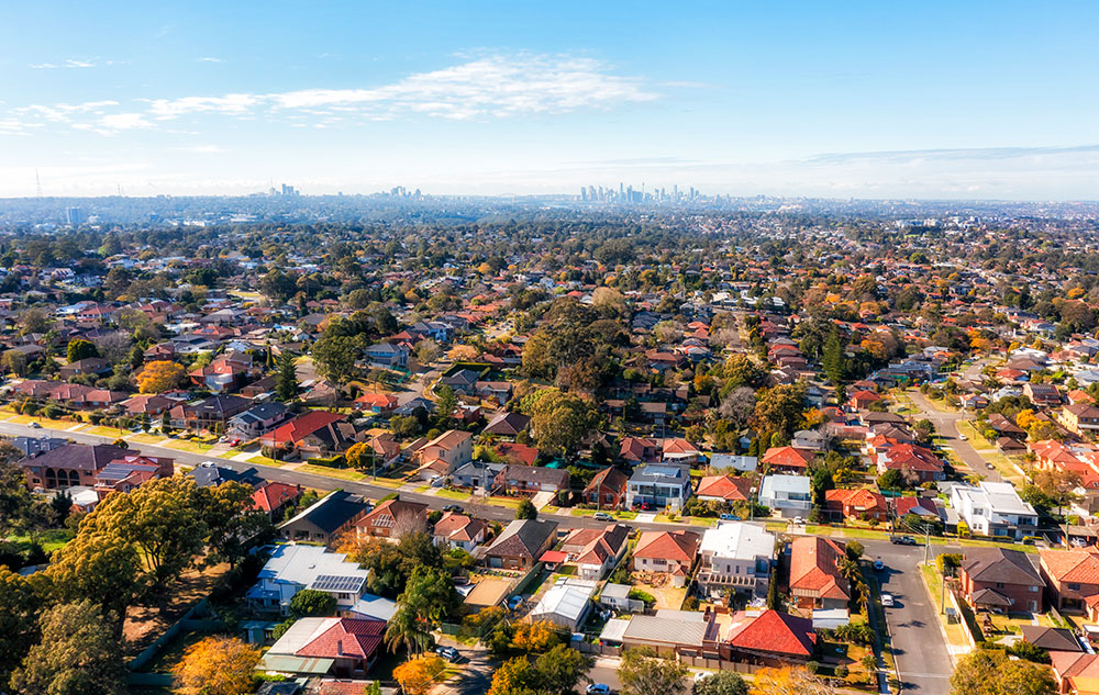 City of Ryde residential suburbs of Greater Sydney in Australia - aerial view towards distant city CBD on horizon.