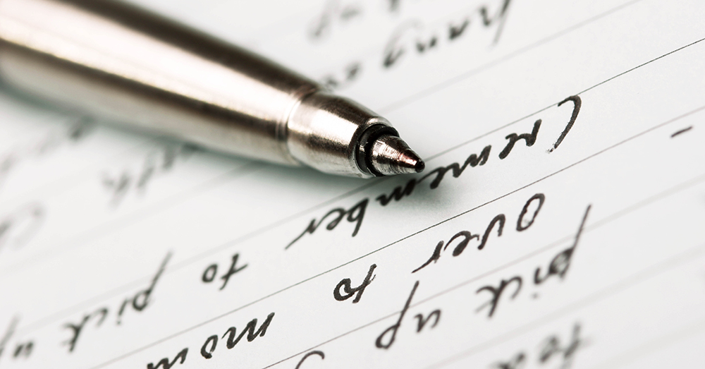 A pen resting on a piece of paper with handwritten text.