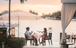 Couple dining outdoors near a lake.