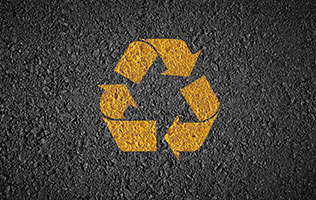 A section of road with the recycling symbol overlaid on it.