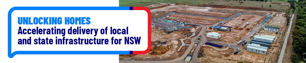 Banner graphic showing a large housing development under construction with the headline "Unlocking Homes – Accelerating delivery of local and state infrastructure for NSW" in a speech-bubble style callout.