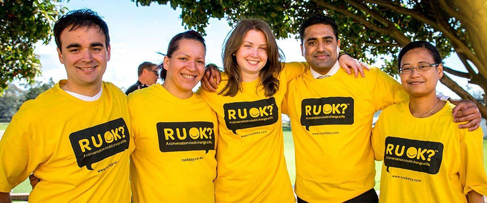 A group of young people sporting bright yellow R U OK T-shirts.