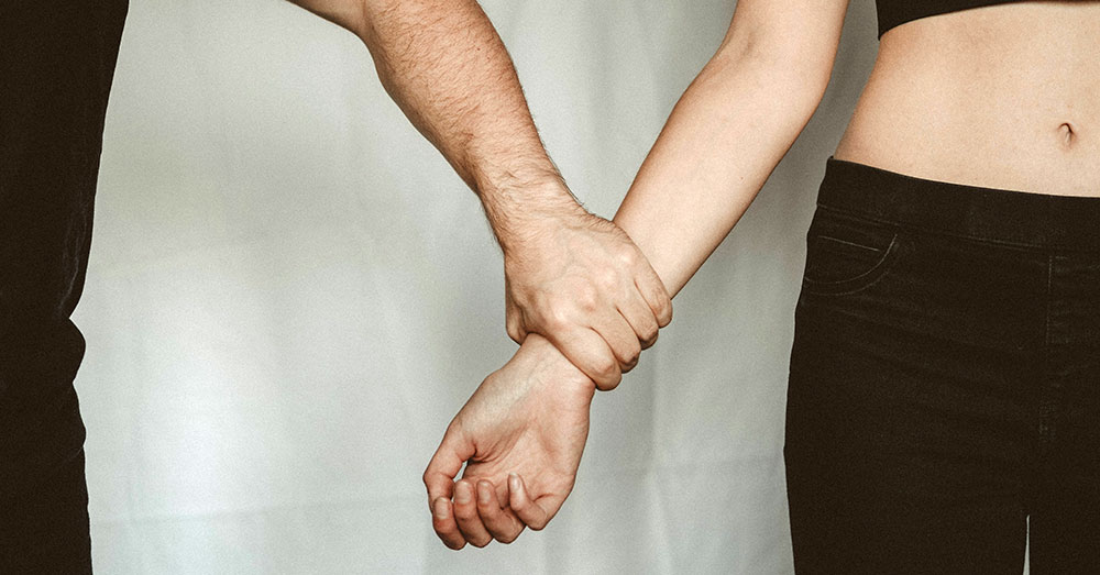 A man grasps a woman's arm.