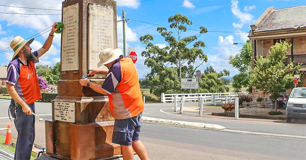 Two men working on restoring a country war memorial.