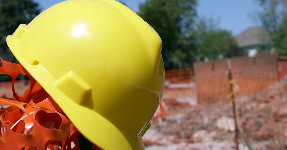 A yellow hard hat resting on a pole on a work site.