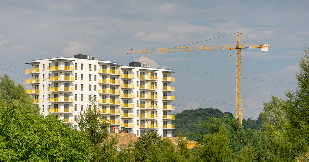 A crane stands near a partially built apartment block.