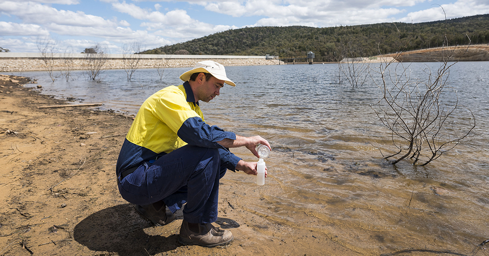 A man tests water at a damn in central NSW.