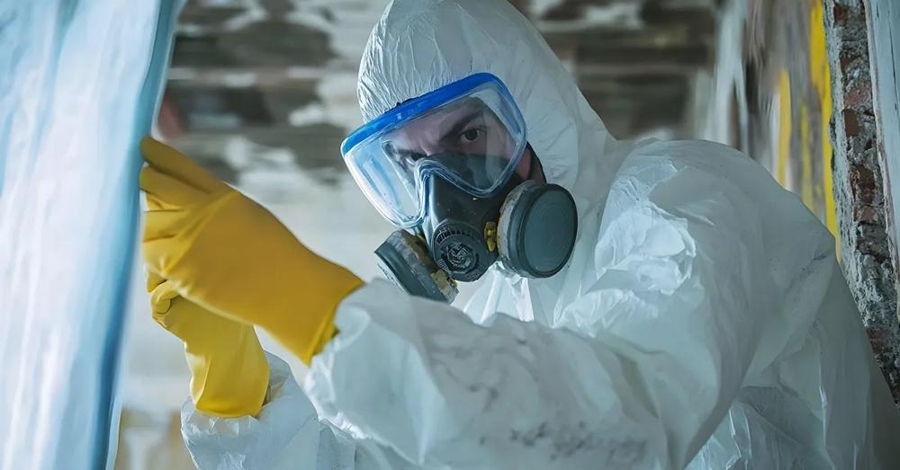 A worker in full PPE removing asbestos.