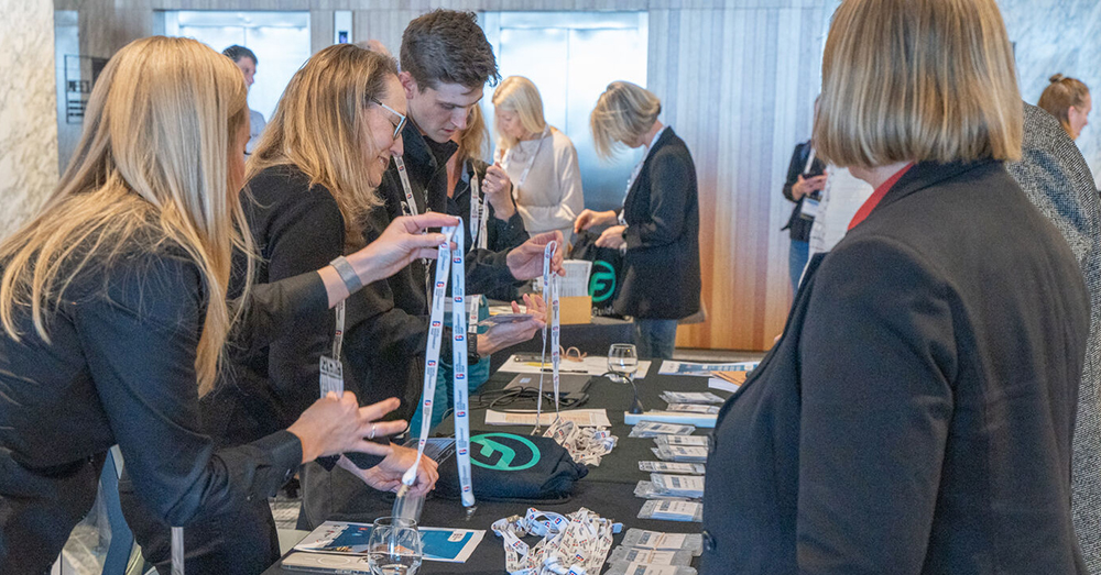 Delegates at an LGNSW conference receiving lanyards and ID tags at the registration desk. 