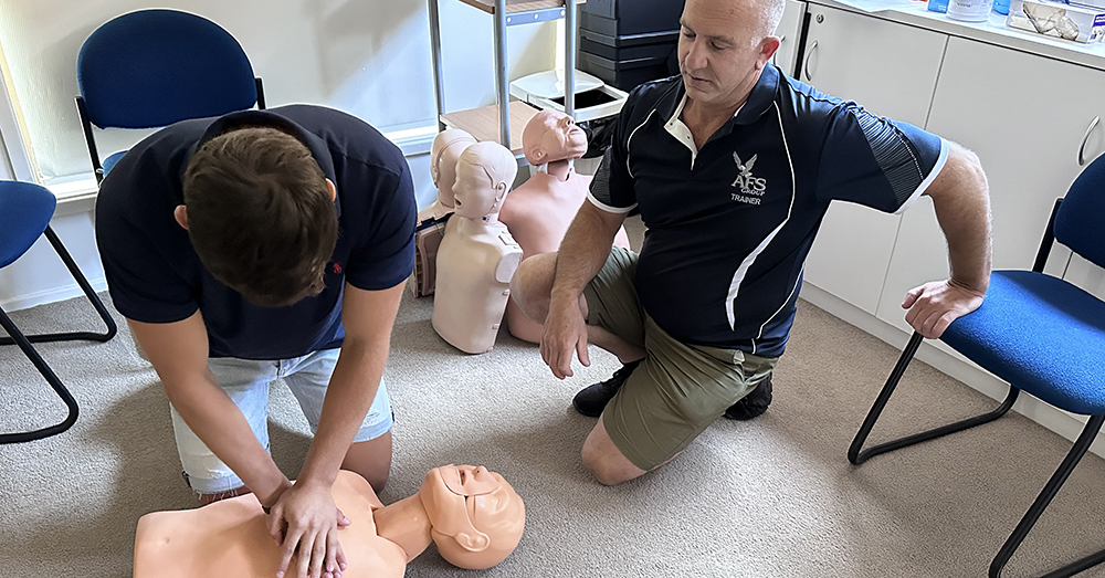 A student practices CPR on a dummy.