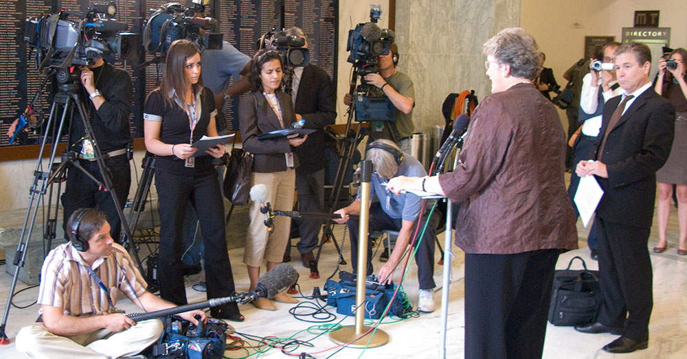 A woman being interviewed by multiple TV journalists.