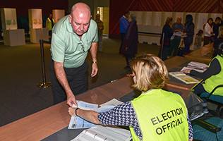 Voter receives his voting documents from a polling booth official.