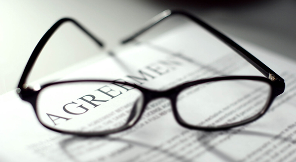 A pair of reading glasses sitting on a paper that is headed "agreement".