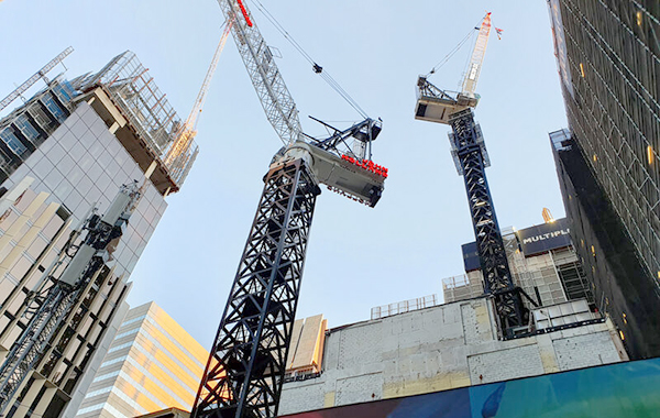 Looking skywards at high-rise buildings under construction and cranes being used to build them.