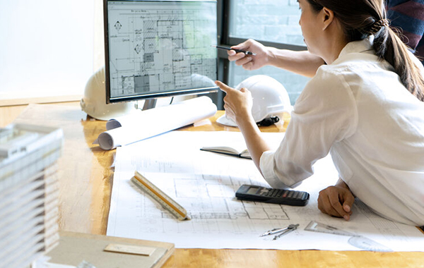 Woman looking at building plans on a PC.