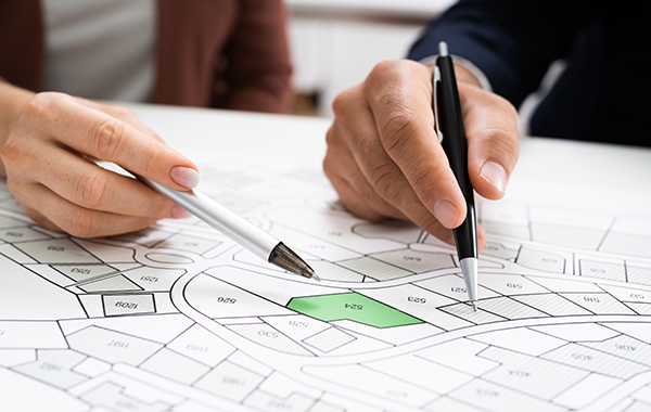 Two people, pens in hand, inspect a plan for a subdivision.