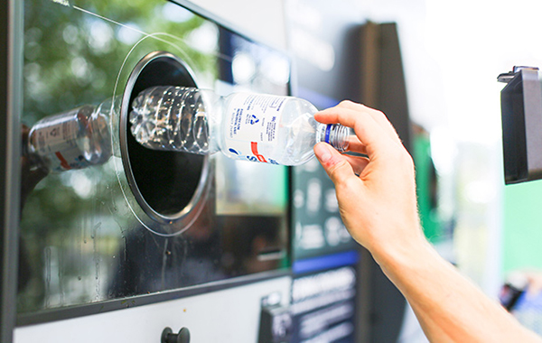 Placing a plastic bottle into a Return and Earn receptacle.